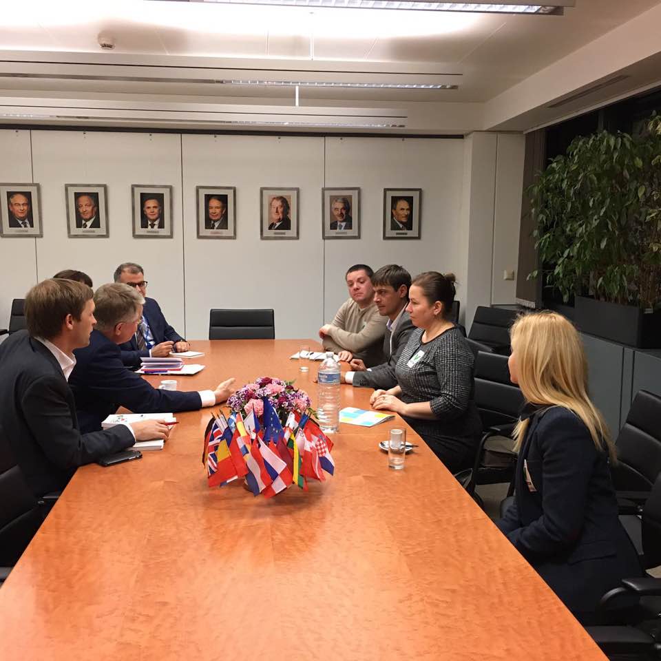 Réunion de personnes autour d'une table avec des drapeaux et des portraits de dirigeants.